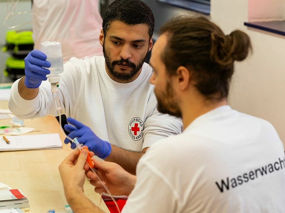 zwei Sanitäter beim herrichten einer Infusion